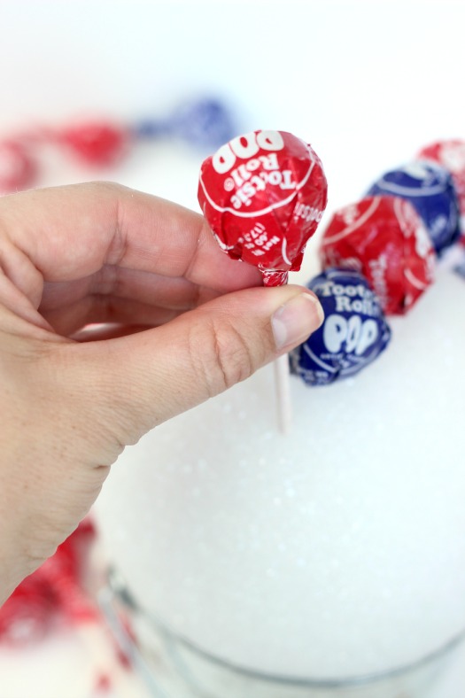 BBQ season is upon us and with Memorial Day and the 4th of July just around the corner, here is a fun patriotic lollipop topiary that the kids will love! I can guarantee that if you bring this to your next gathering it will be the hit of the party! A quick and easy lollipop topiary made in about 10 minutes.