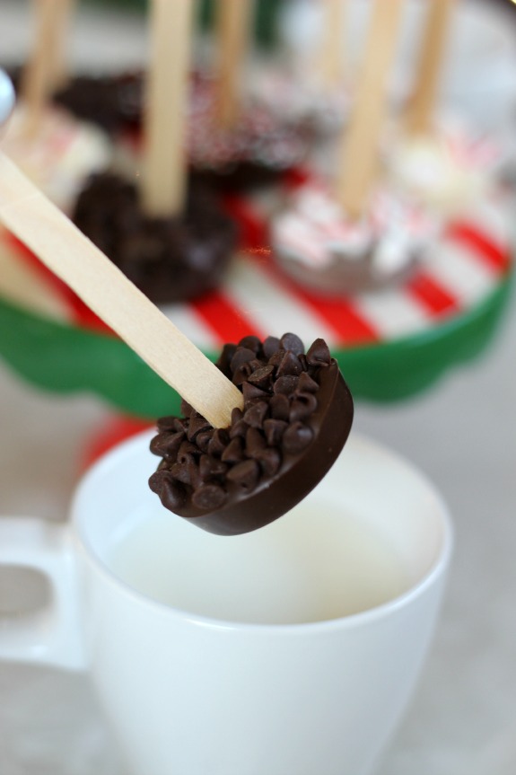 chocolate chip hot chocolate on a stick with white mug of hot milk