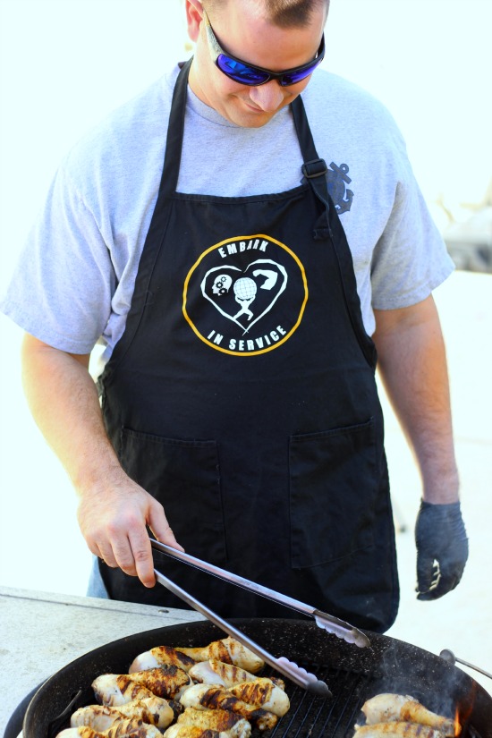 man with apron grilling chicken