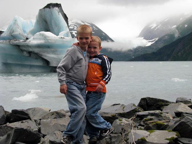 two little boys standing in front of an iceberg