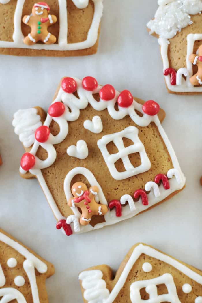 gingerbread house cookie decorated with vanilla buttercream and red hots candies.