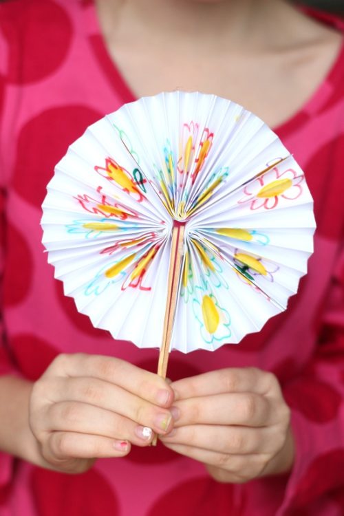 child holding paper pocket fan