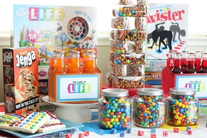 jars of candy and orange soda bottles with board games on table