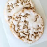 Two iced oatmeal cookies on parchment paper.