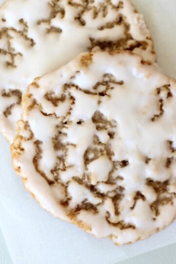 Two iced oatmeal cookies on parchment paper.