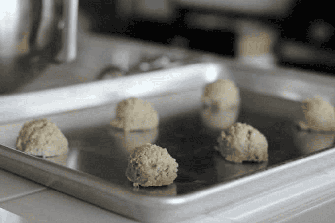 Balls of oatmeal cookie dough on metal baking sheet.