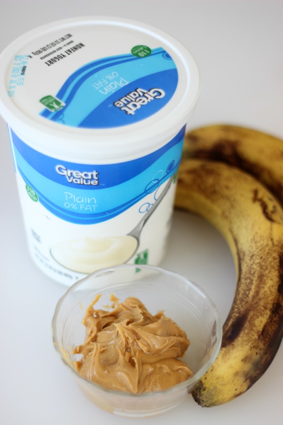 container of plain yogurt next to bananas and small bowl of peanut butter