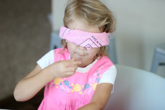 blindfolded child trying a piece of candy