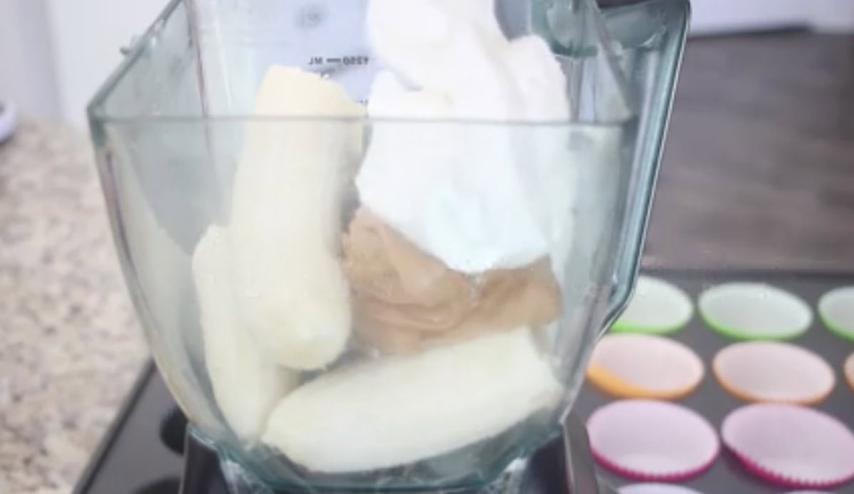 Blender with bananas, yogurt and peanut butter inside.