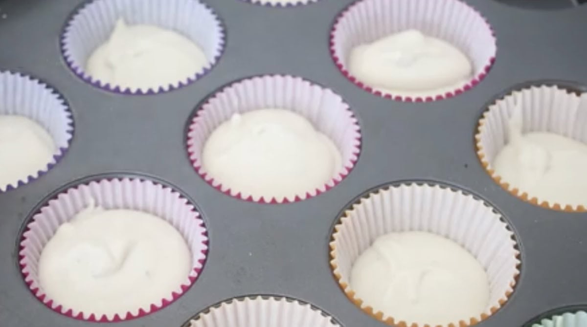 Muffin pan with muffin liners and ice cream mixture in each cup.