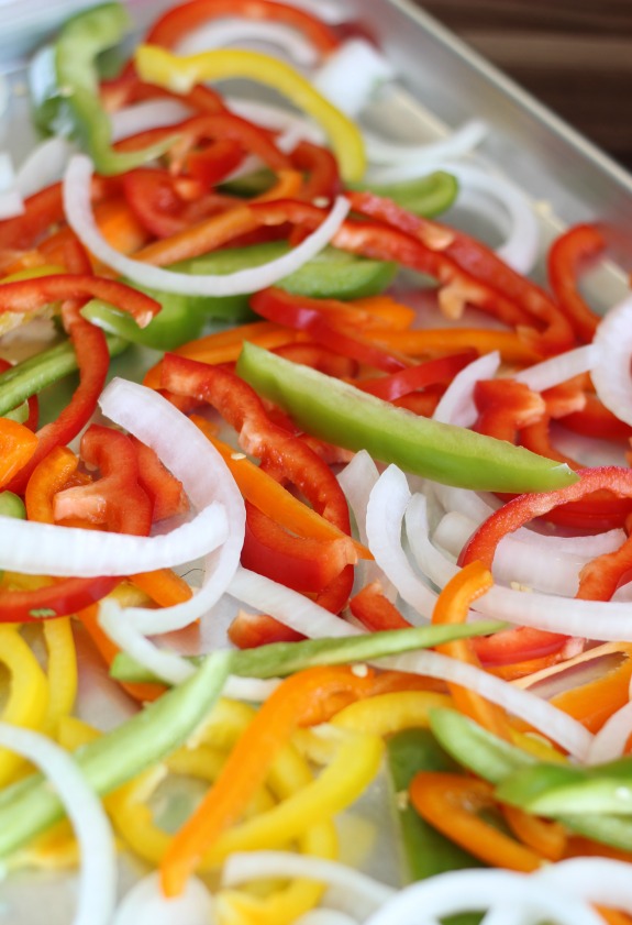 sliced bell peppers and onions in sheet pan