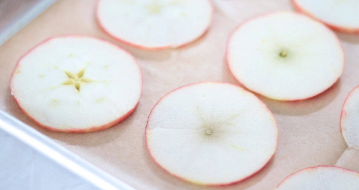 Apple slices on a baking sheet with parchment paper.