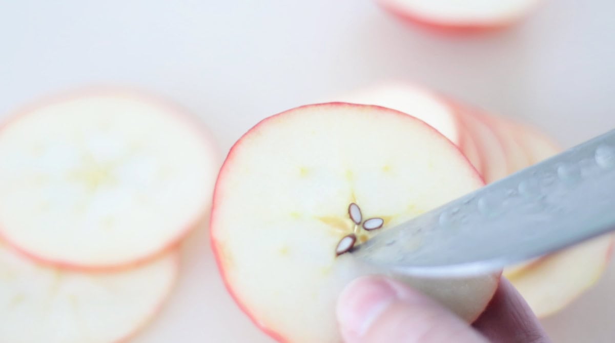 Knife removing seeds from apple slice.