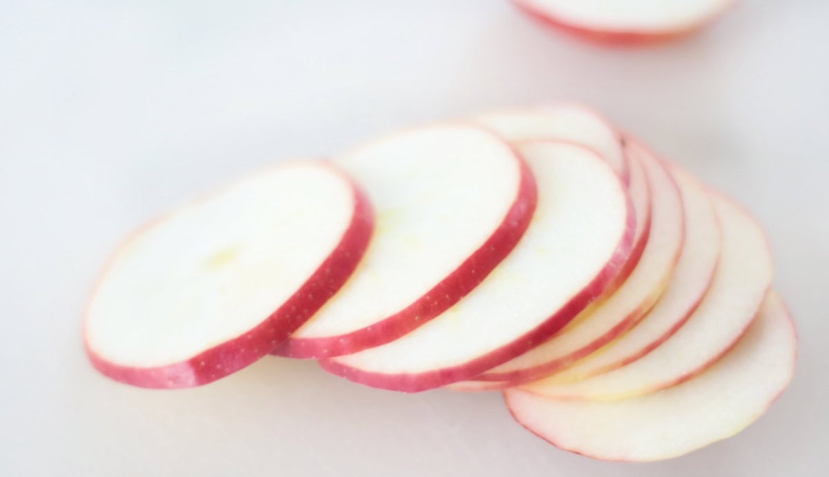 Slices of apples on a white cutting board.
