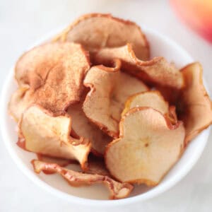 White bowl of baked apple chips.