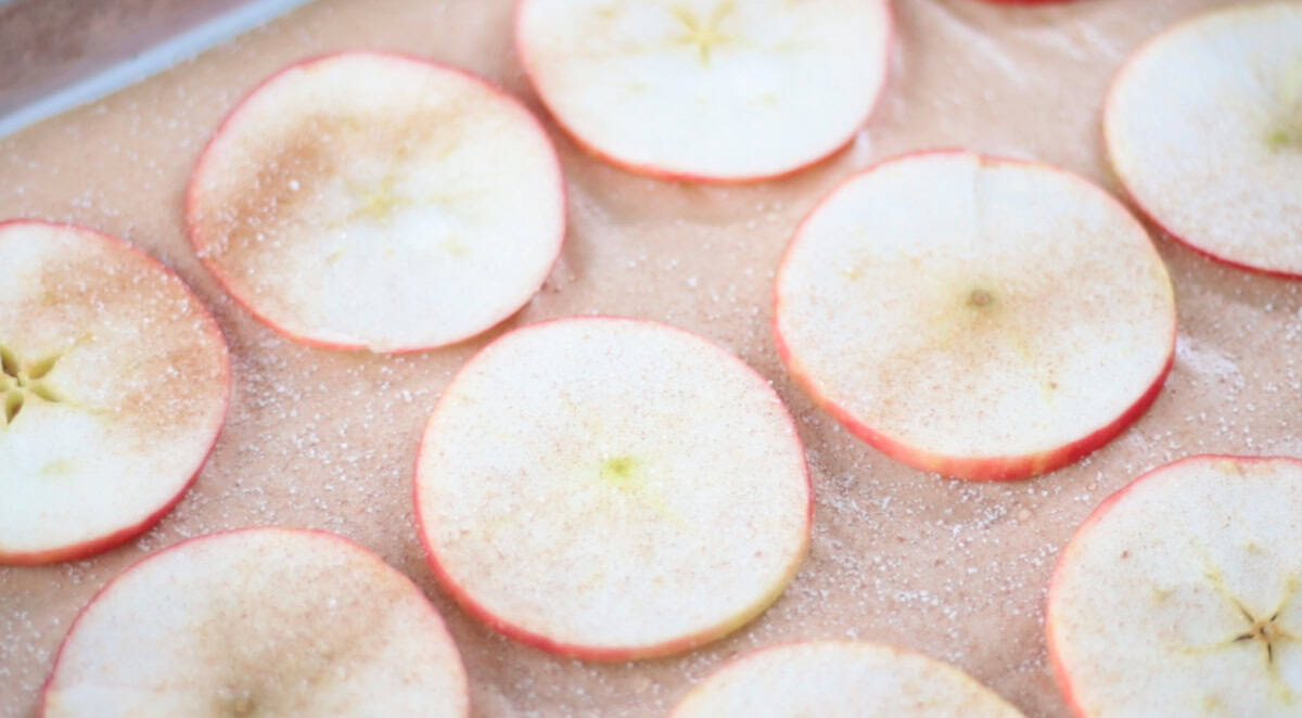 Apple slices on baking sheet sprinkled with cinnamon and sugar.