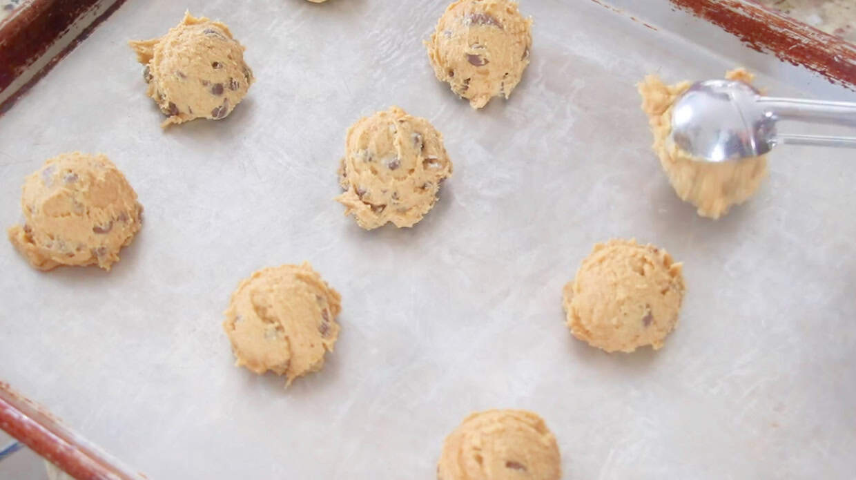 Baking sheet with scoops of pumpkin chocolate chip cookie dough spaced apart.