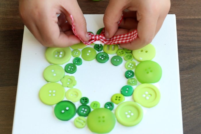 child gluing ribbon onto wreath