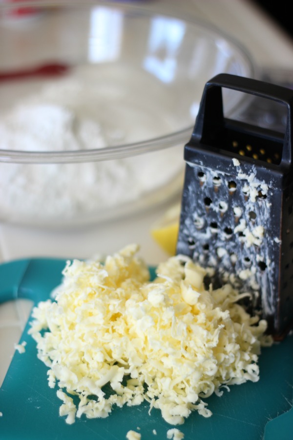 shredded butter and grater on blue cutting board