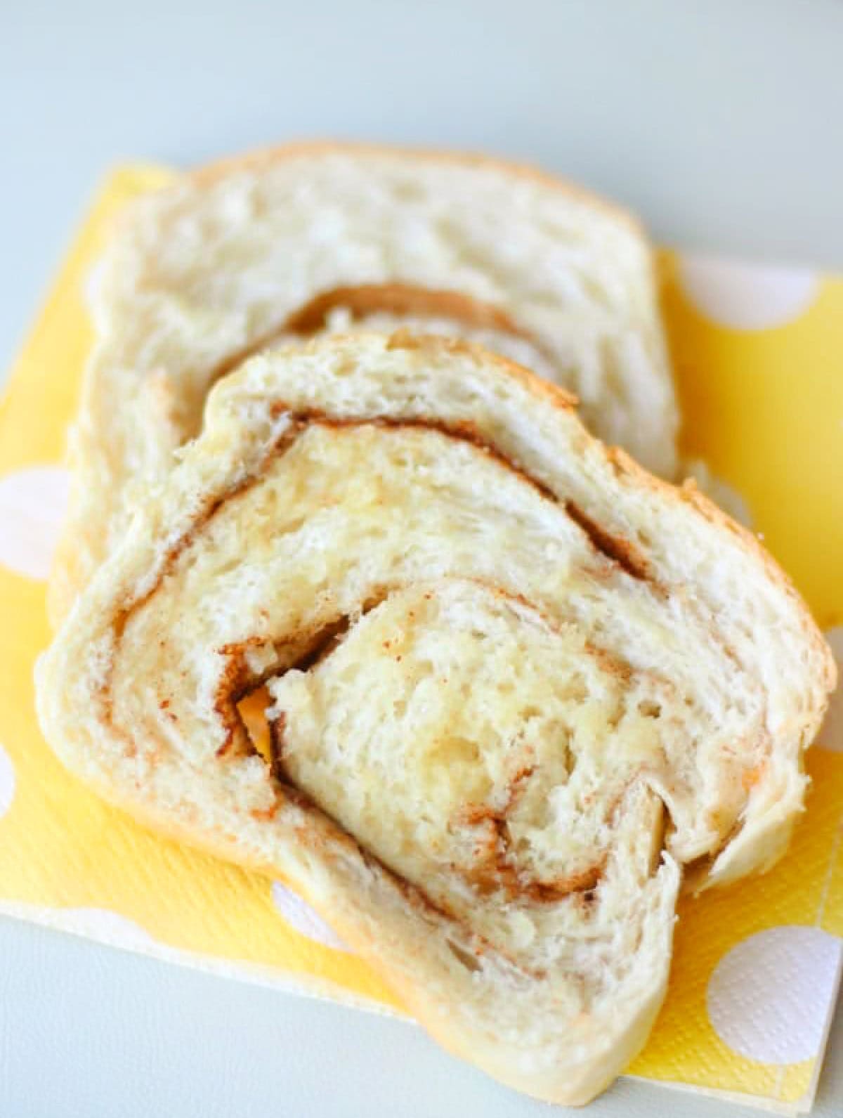 Two slices of buttered cinnamon swirl bread on yellow napkin.