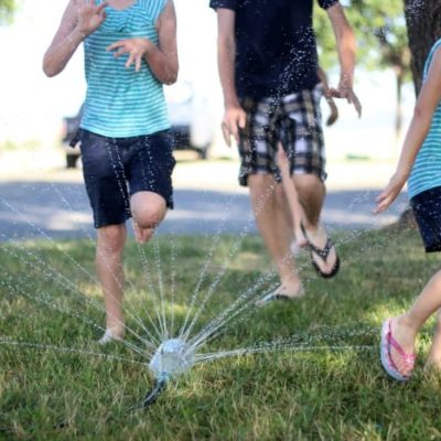 kids running through sprinkler