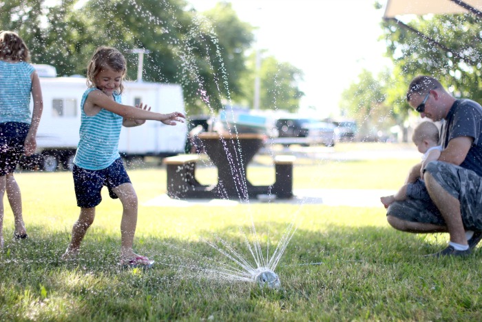 girl running through sprinkler