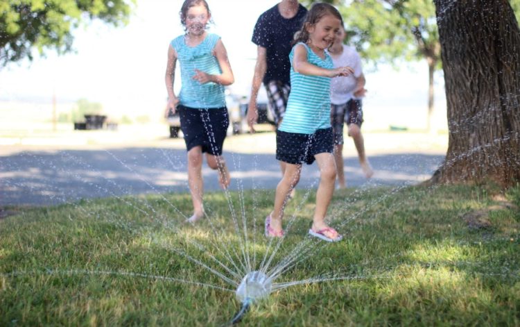 kids running through sprinkler