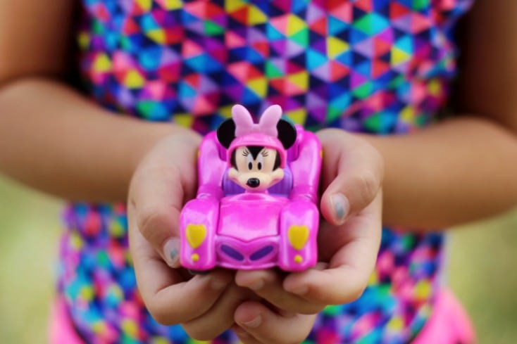 little girl holding pink Minnie mouse car