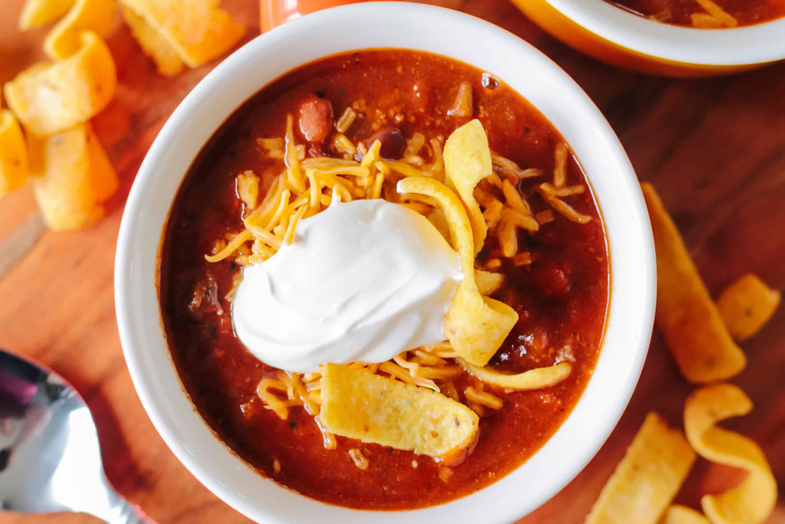 Bowl of chili with chips, cheese and sour cream.