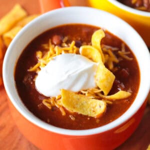 Bowl of turkey chili with cheese, sour cream and chips.