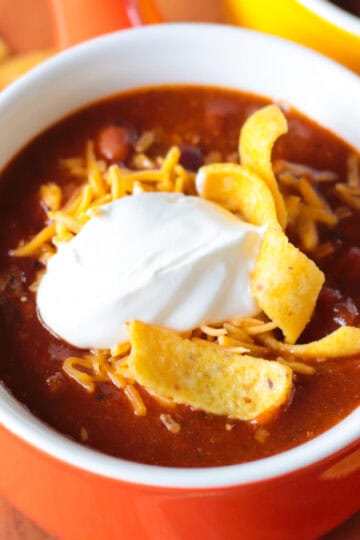 Bowl of turkey chili with cheese, sour cream and chips.