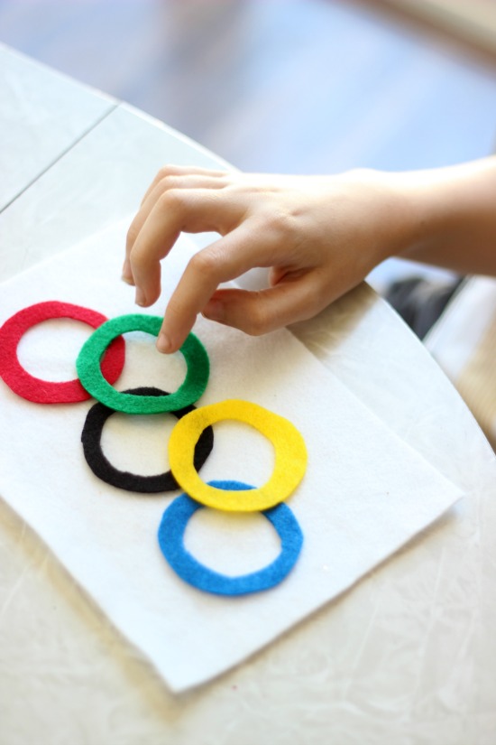 child gluing rings onto olympic flag