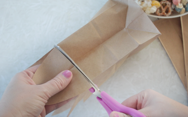 hand holding scissors and trimming brown bag