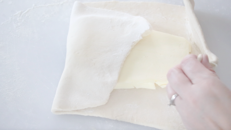 hand folding dough around butter