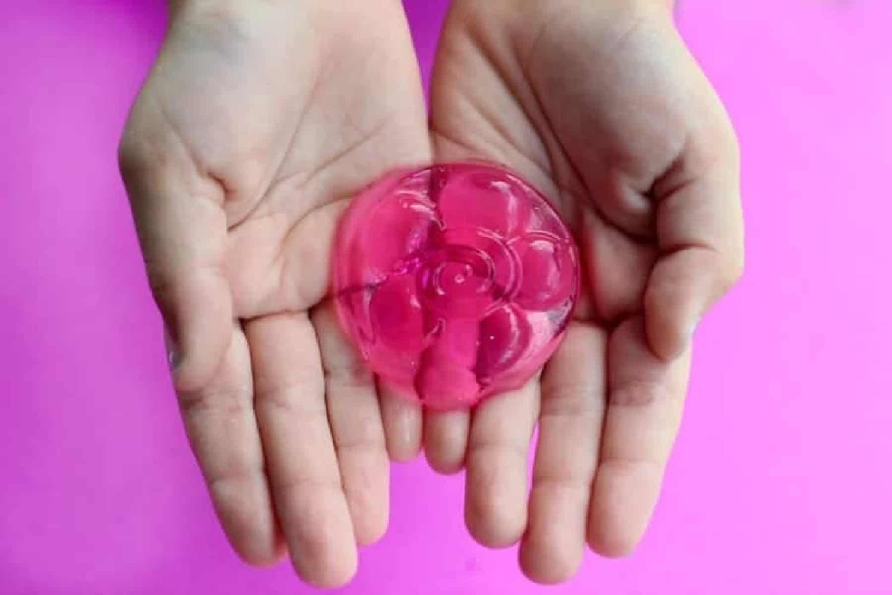 Hands holding round pink jelly soap.