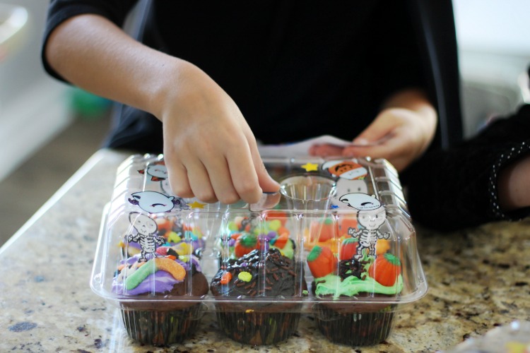 child decorating cupcake tray with stickers at halloween cupcake decorating party