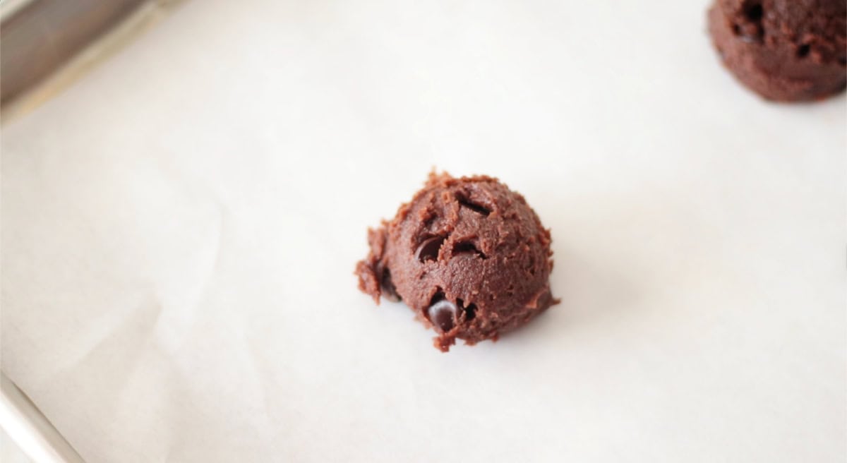 Chocolate pumpkin cookie dough on baking sheet with parchment paper.