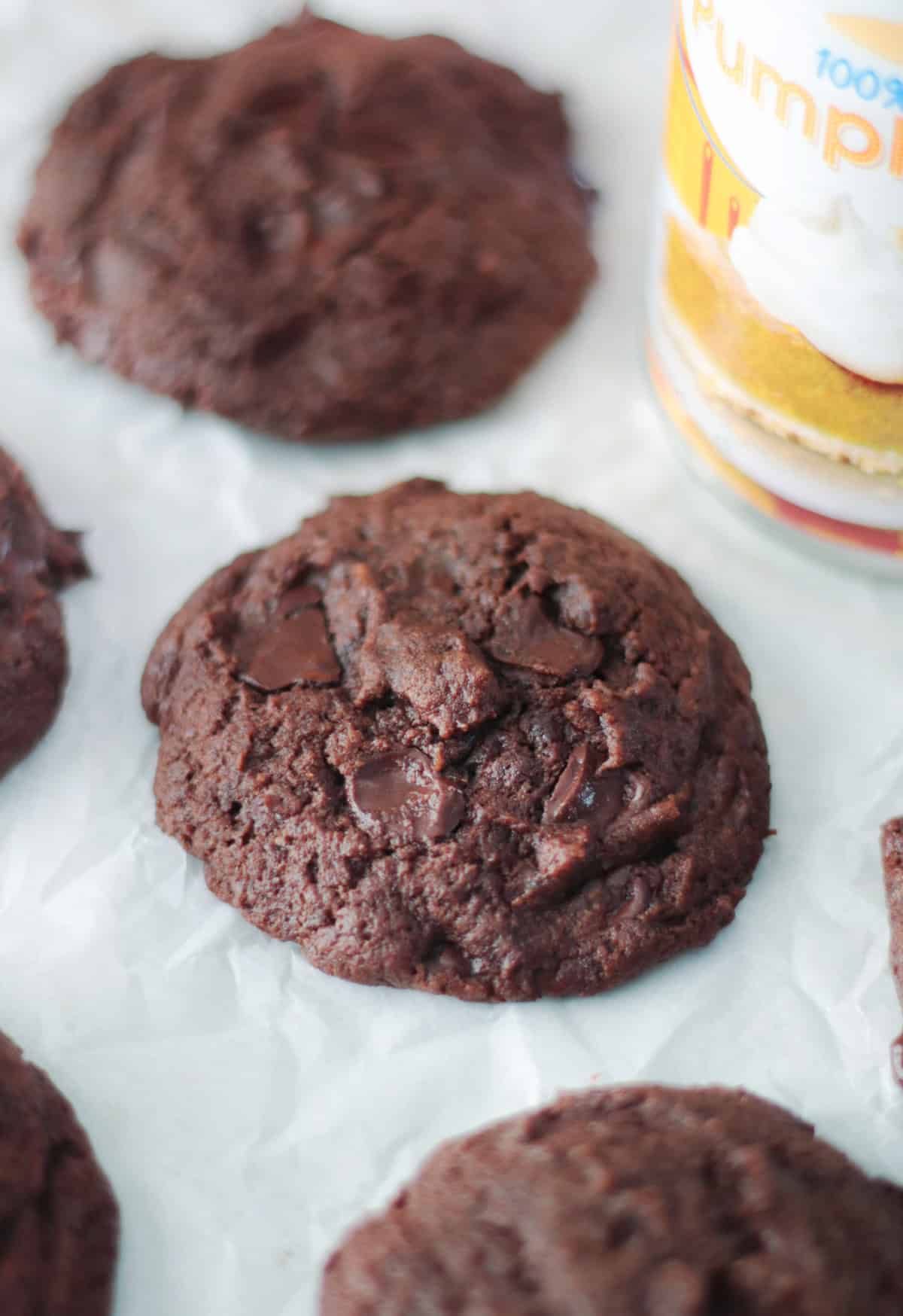 Chocolate pumpkin cookies on parchment paper next to can of pumpkin puree.