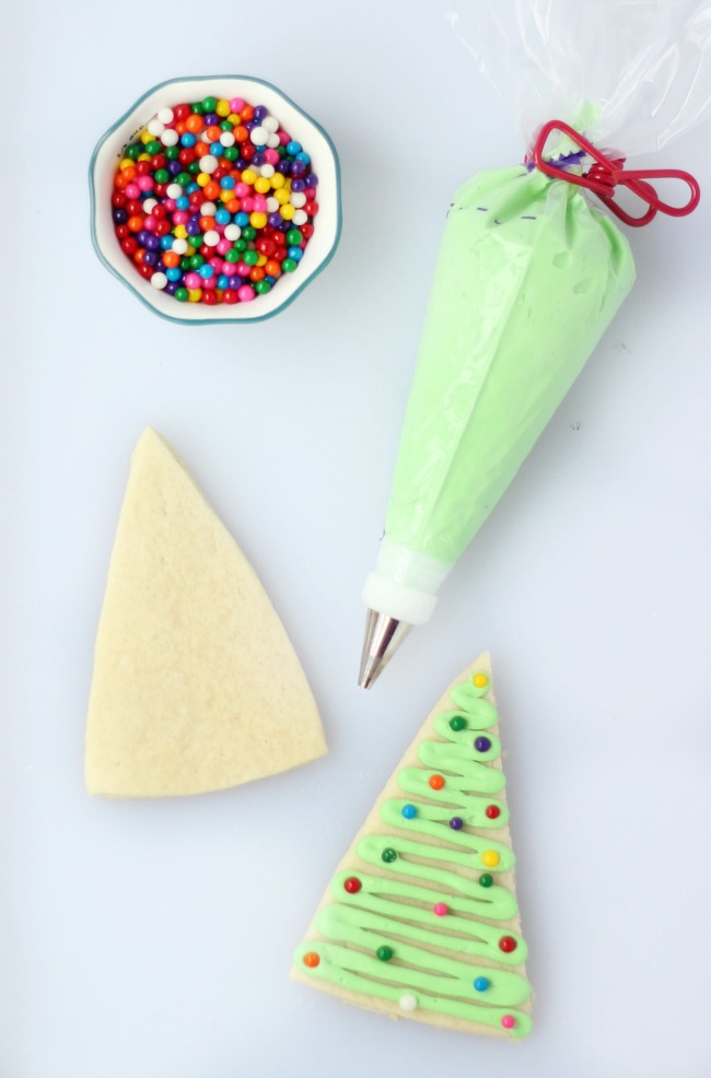 baked sugar cookie with frosting tube and bowl of sprinkles