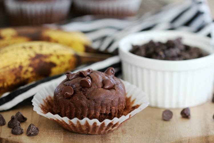 chocolate banana muffin on cutting board next to bowl of chocolate chips