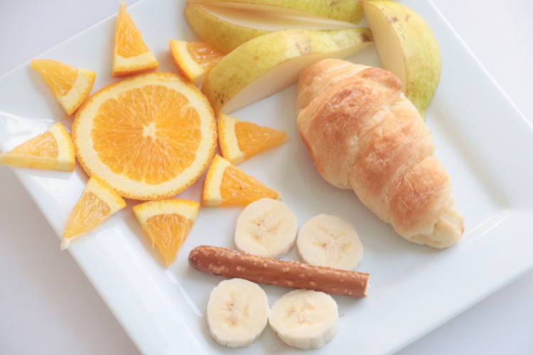 plate with fruit and croissant arranged to look like butterfly life cycle