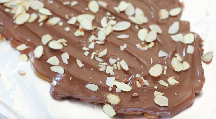 melted chocolate spread over toffee sprinkeld in sliced almonds