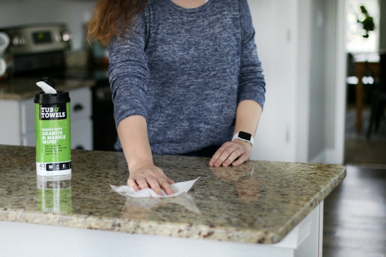 wiping granite countertop with cleaning wipe