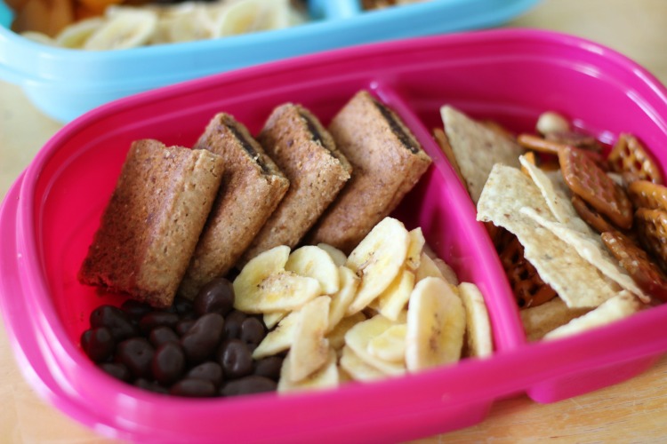 sweet road trip snacks in container fig bars, chocolate raisins and banana chips