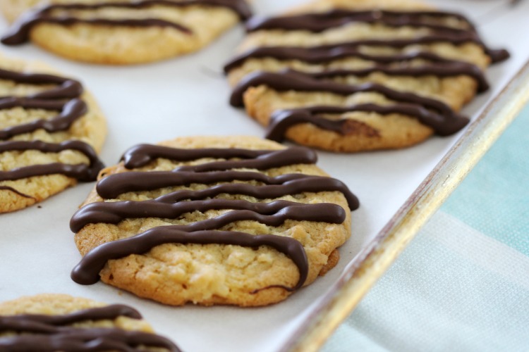 chocolate drizzled crispy coconut cookies on baking sheet