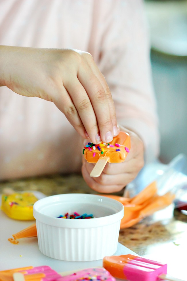 adding sprinkles to candy popsicles