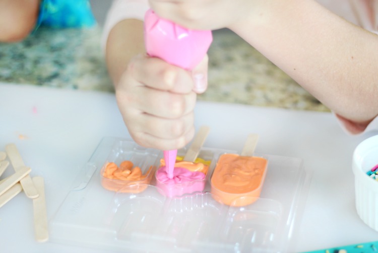 child piping melting candies for lemonade cupcakes into mold