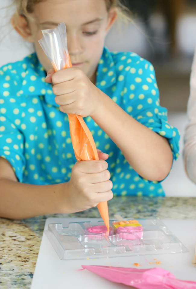 child piping melting candies into mold