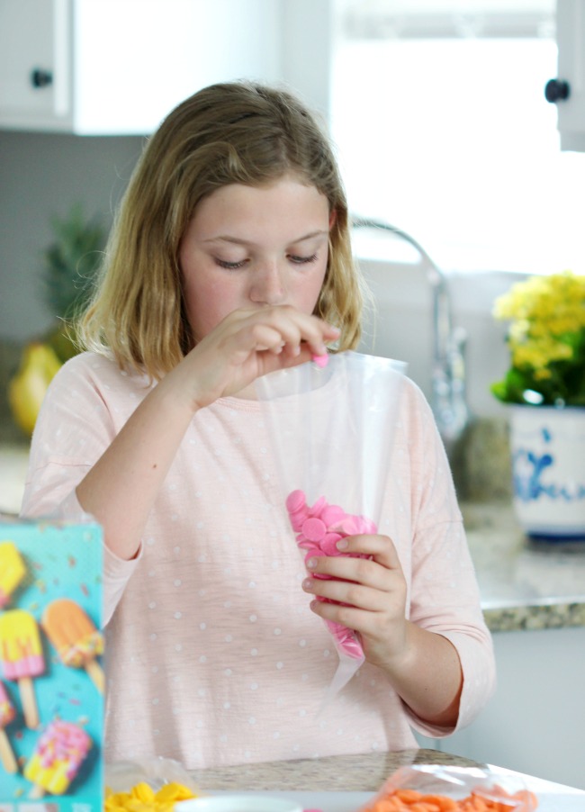 child filling frosting bag with candy melts