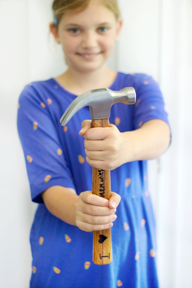 child holding a hammer with hand lettering on it